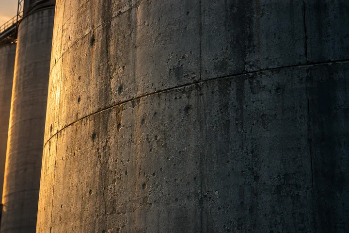 Warm light across the weathered concrete of a grain silo