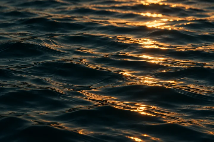 Golden light reflected in deep teal water